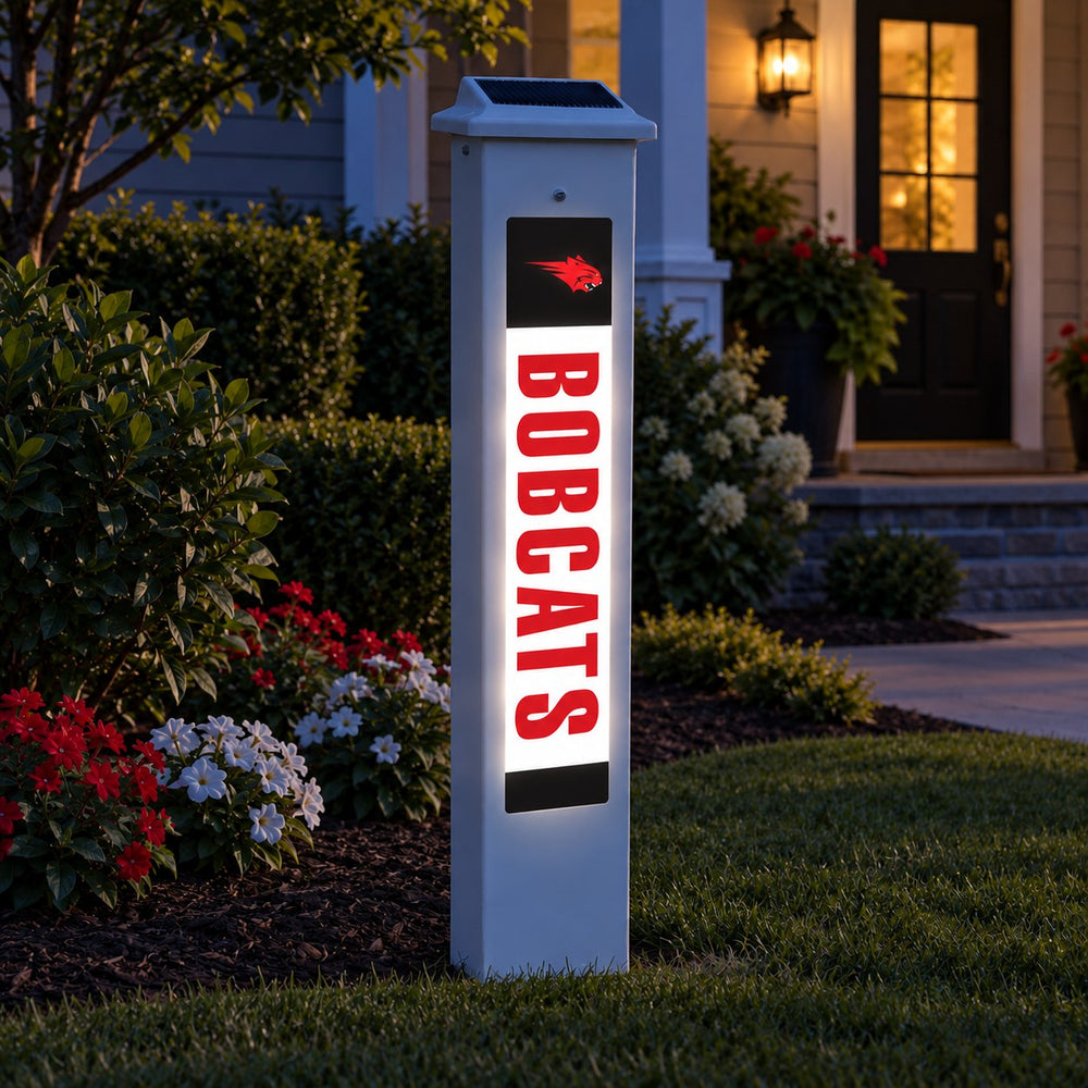 Western Dubuque Bobcats Solar Glow Post lit up at dusk beside a front walkway.